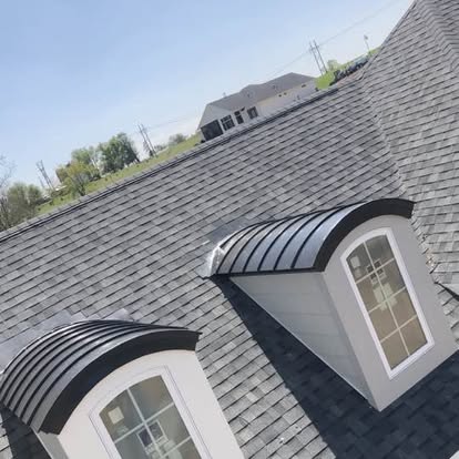 Two curved metal dormer roofs on a shingled house