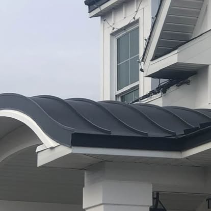 Curved black metal entry canopy on a white home